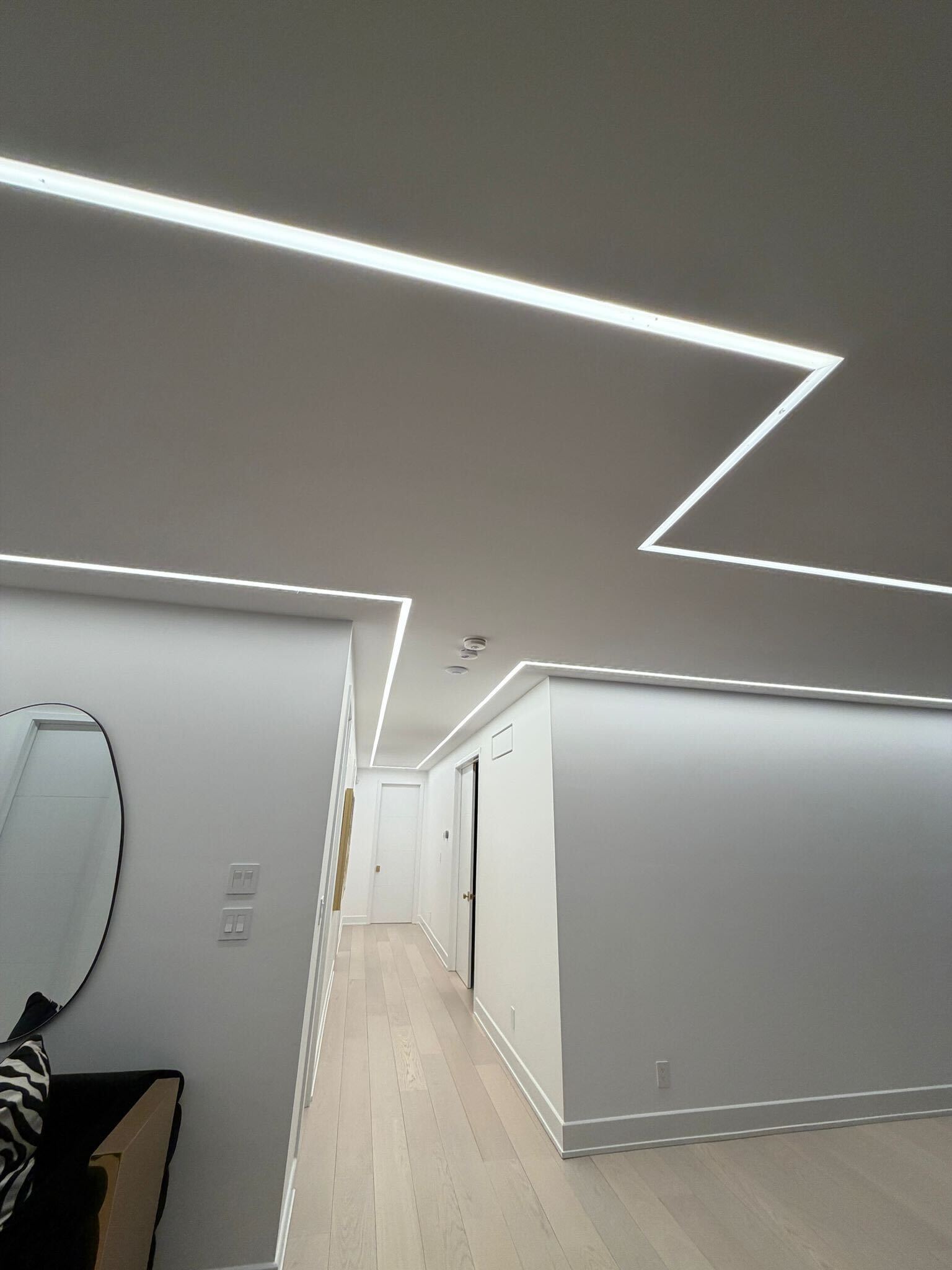 Hallway with geometric angular LED strip patterns on ceiling and wall